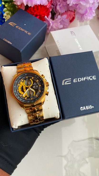 Gold-tone sport watch on a cushion beside watch boxes.